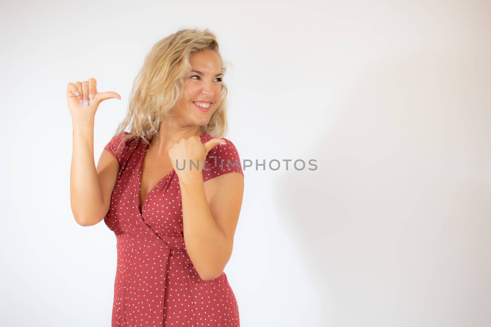 Beautiful smiling blonde woman in a red dress pointing something