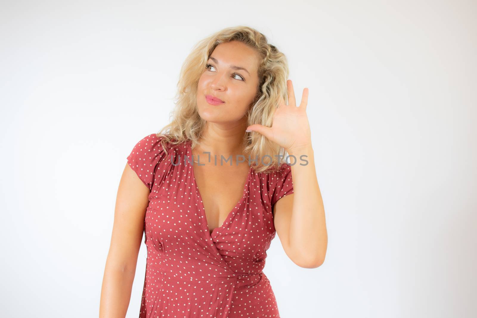 Pretty blonde woman in red dress making listening gesture