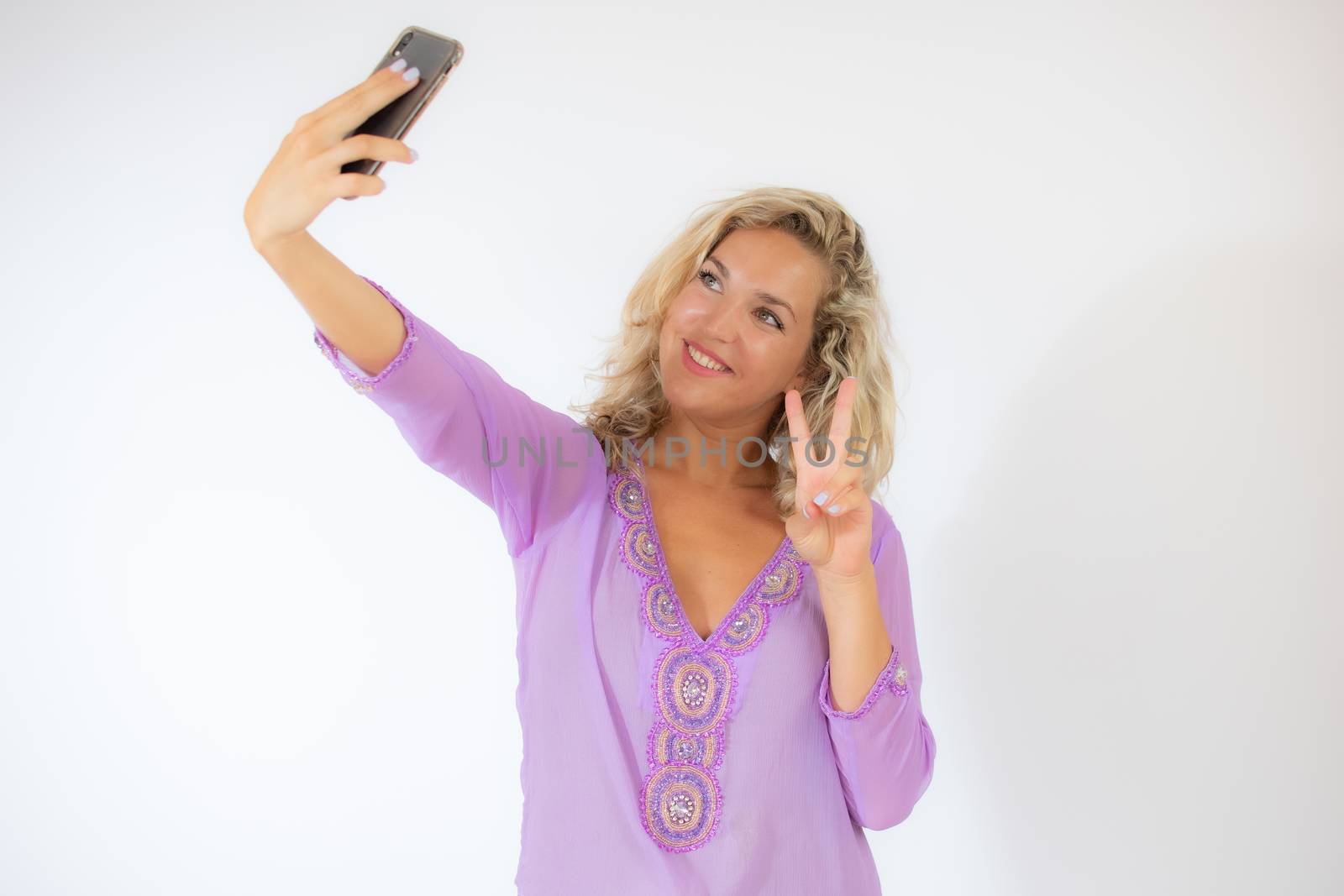 Pretty blonde woman in lila caftan smiling taking a photo