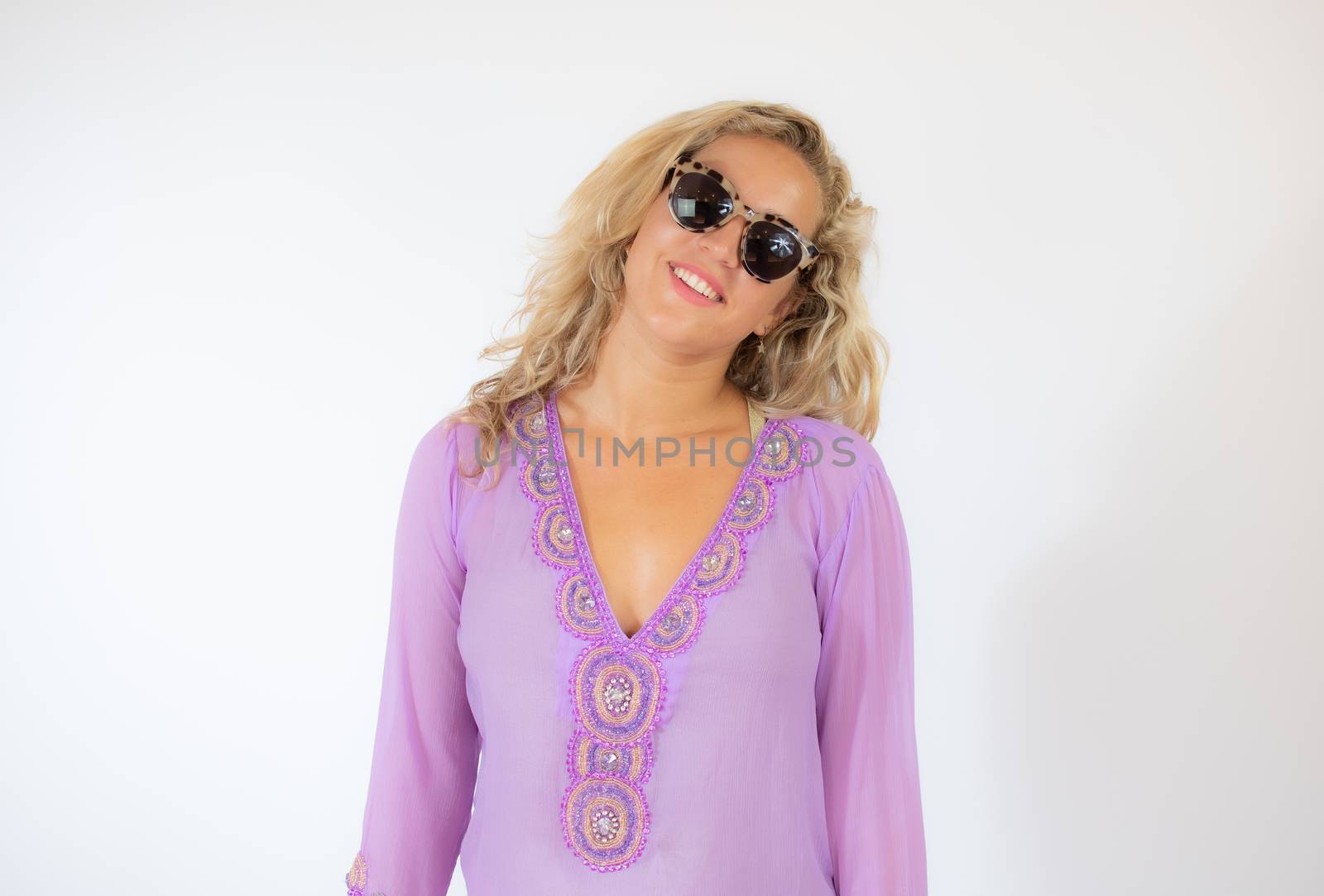 Pretty blonde woman wearing sunglasses and with a lilac caftan smiling