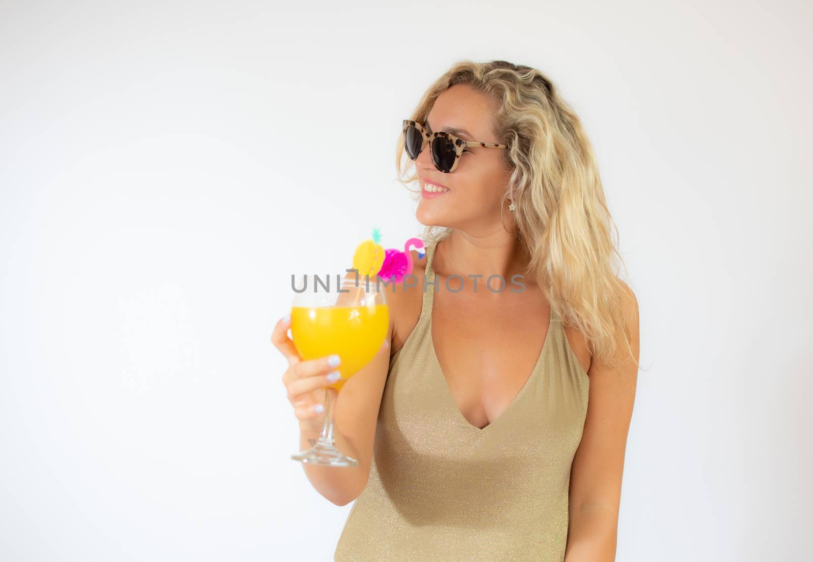 Pretty smiling blonde woman with sunglasses in golden swimsuit with a fruit cocktail