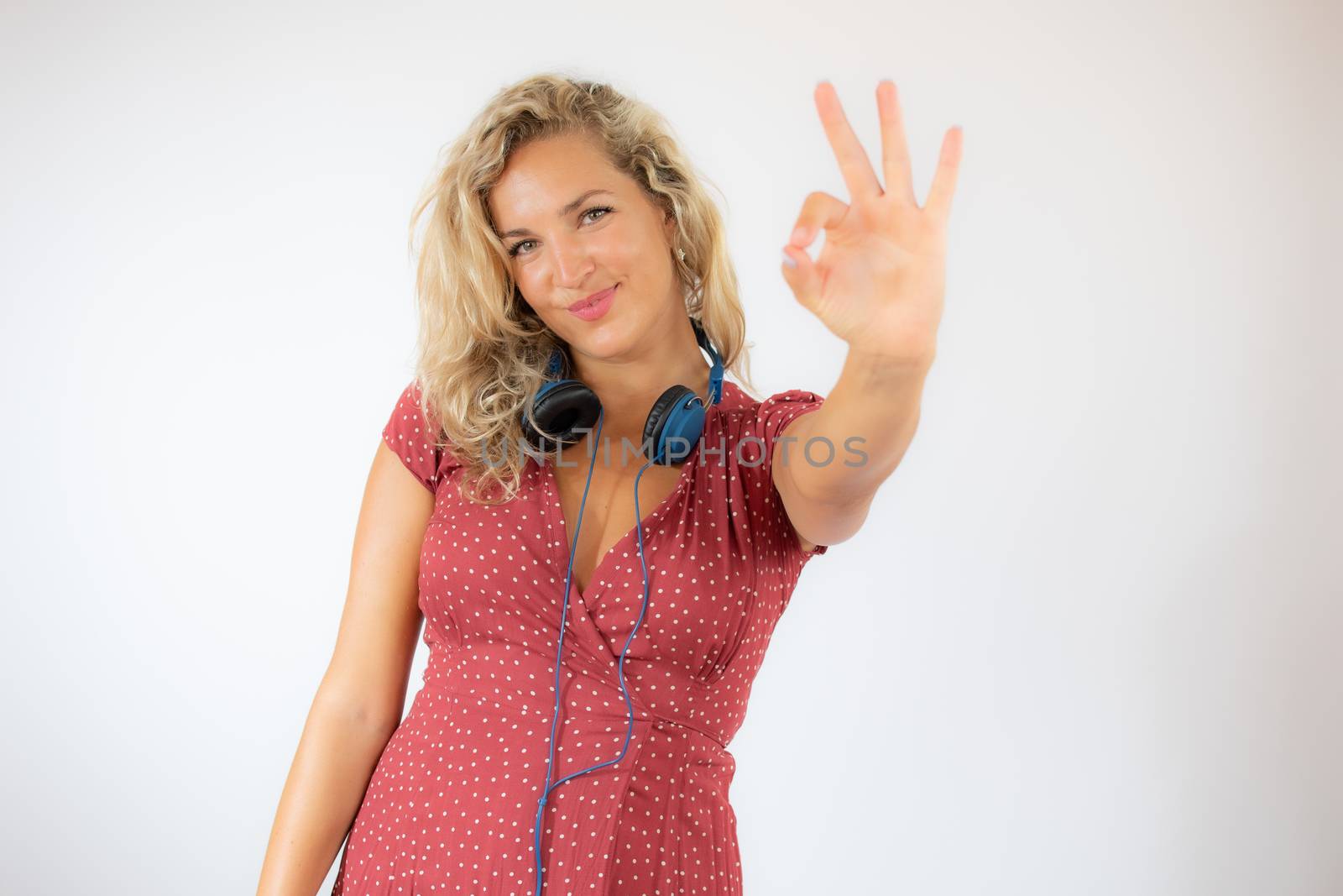 Pretty smiling blonde woman in red dress with headphones