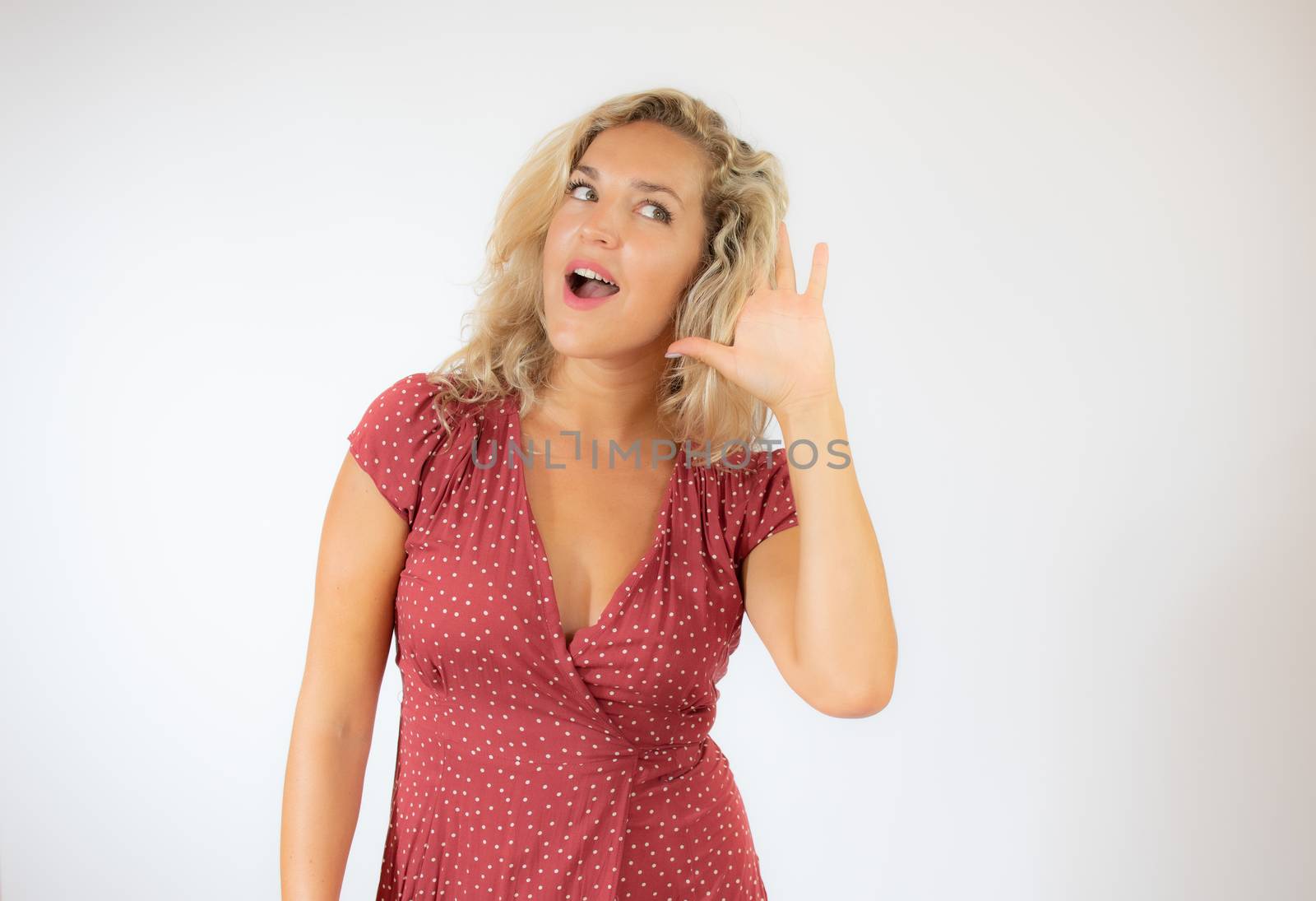 Pretty blonde woman in red dress making listening gesture