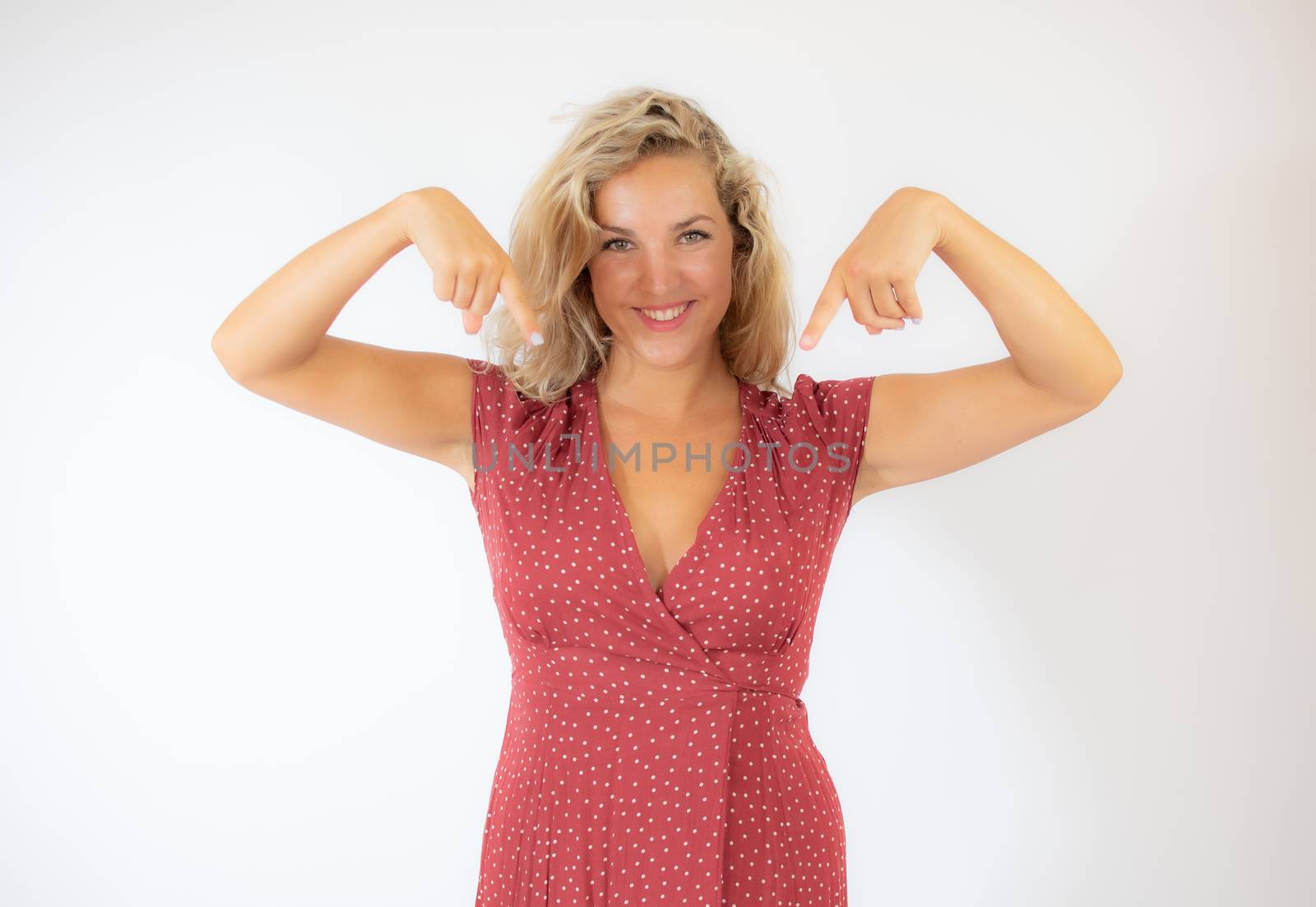 Beautiful smiling blonde woman in a red dress pointing something