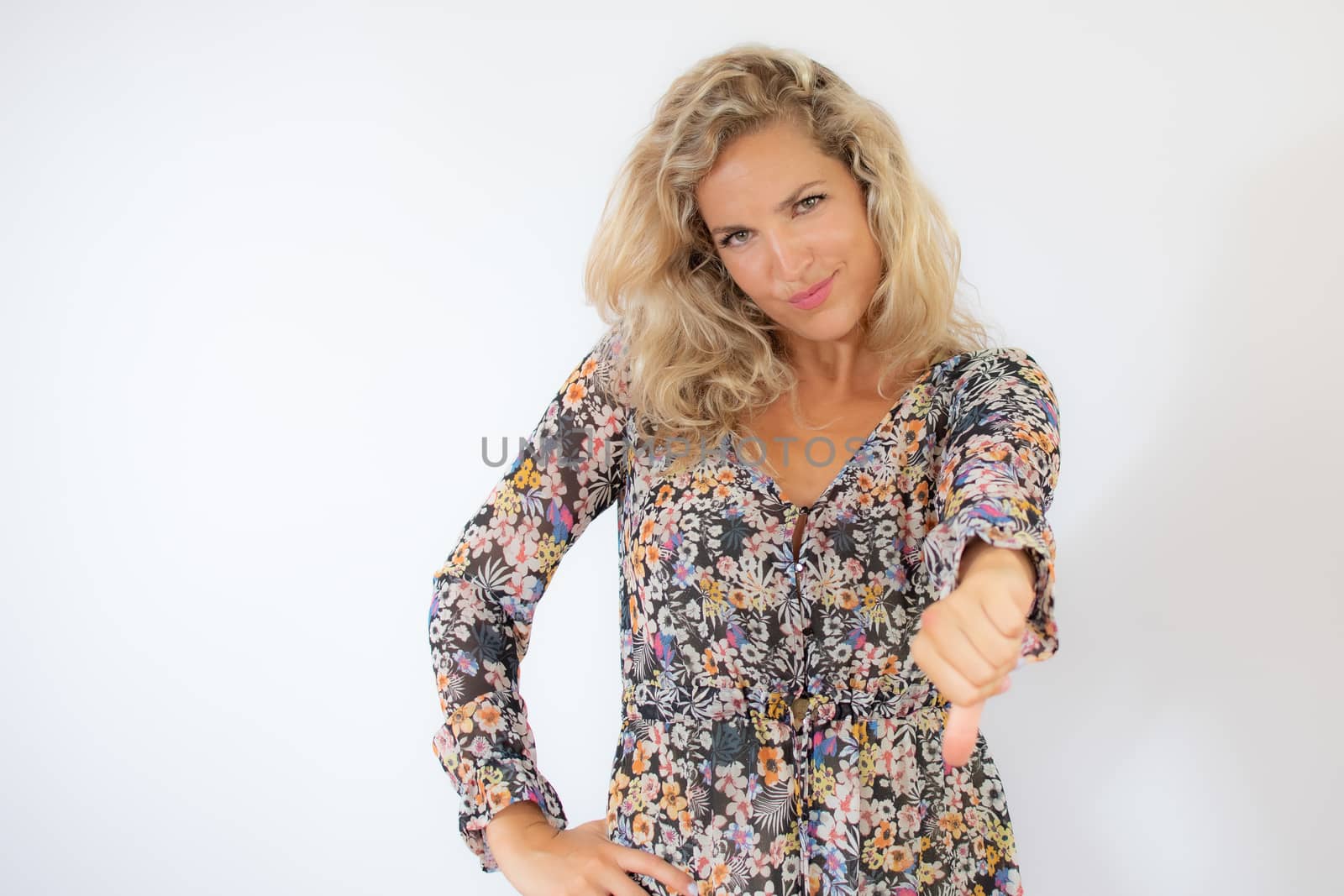 Pretty blonde woman in a flowery dress gesturing on white background