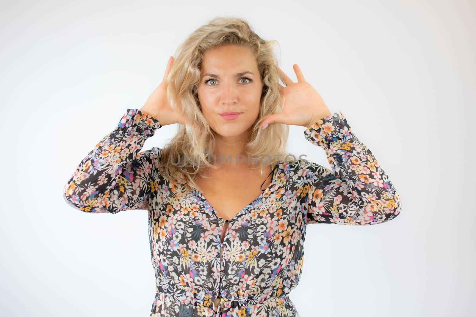 Pretty blonde woman in a flowery dress gesturing on white background