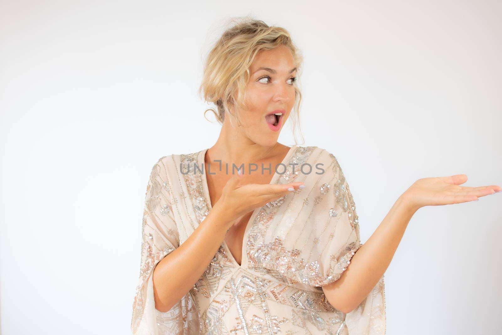 Smiling pretty blonde woman in a party dress gesturing on white background