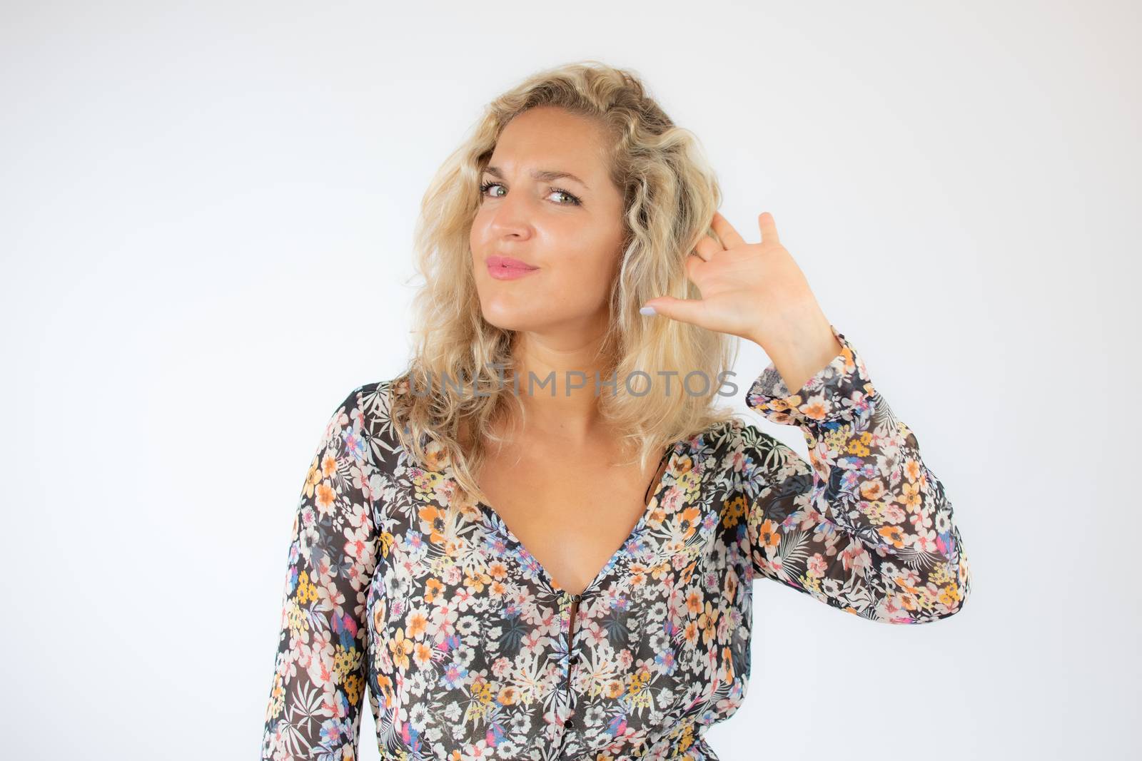 Pretty blonde woman in a flowery dress gesturing on white background