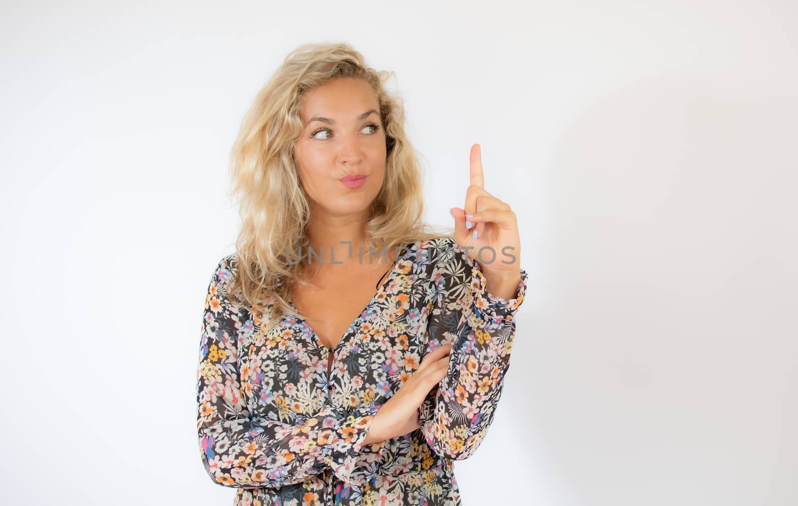 Pretty blonde woman in a flowery dress gesturing on white background