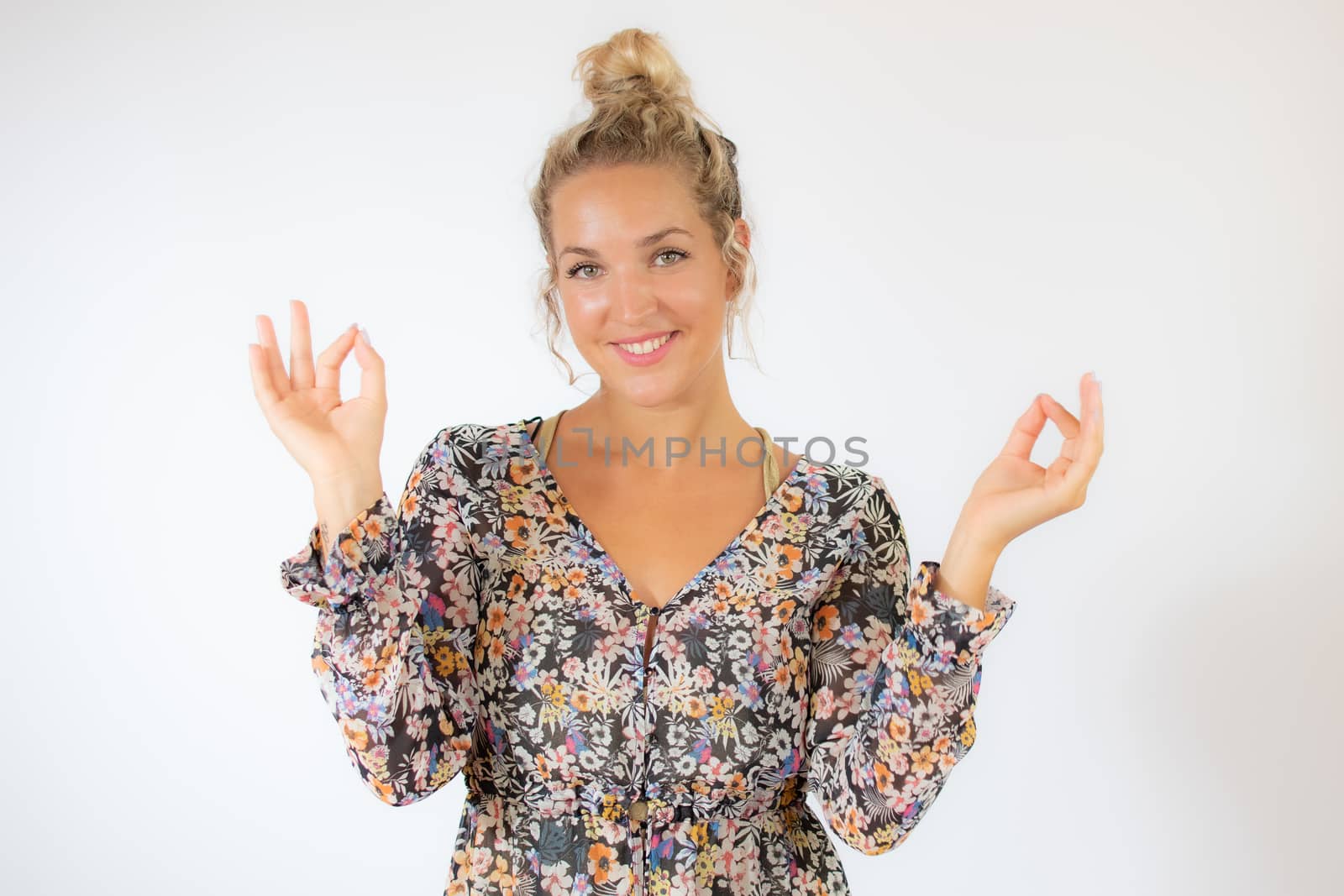 Pretty blonde woman in a flowery dress gesturing on white background