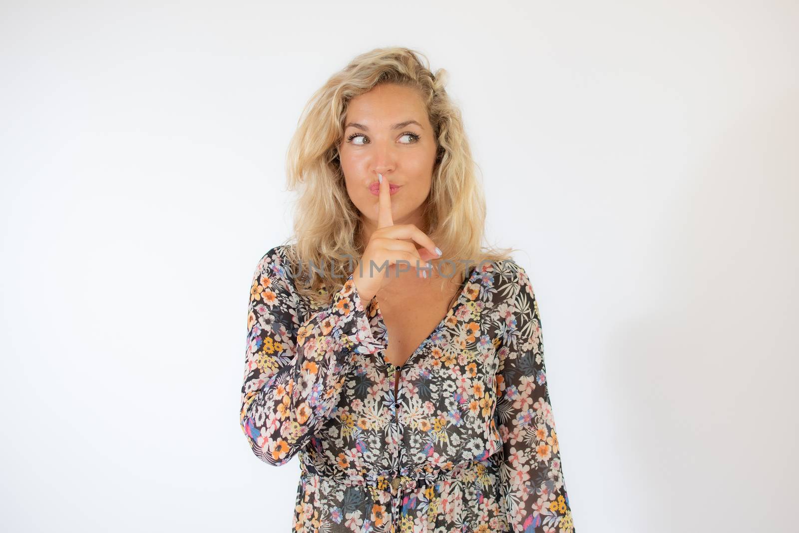 Pretty blonde woman in a flowery dress gesturing on white background