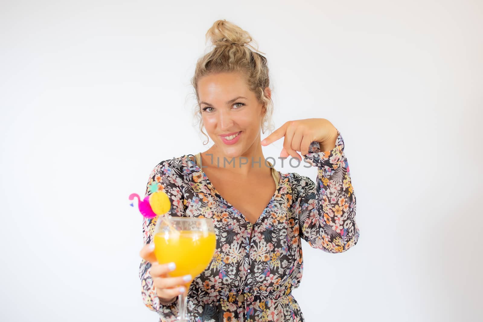 Pretty blonde woman in a flowery dress with a cocktail on white background