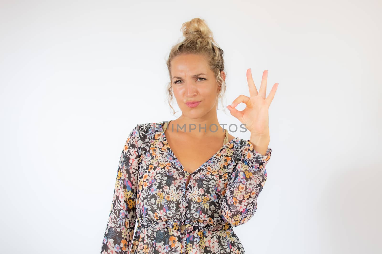 Pretty blonde woman in a flowery dress gesturing on white background