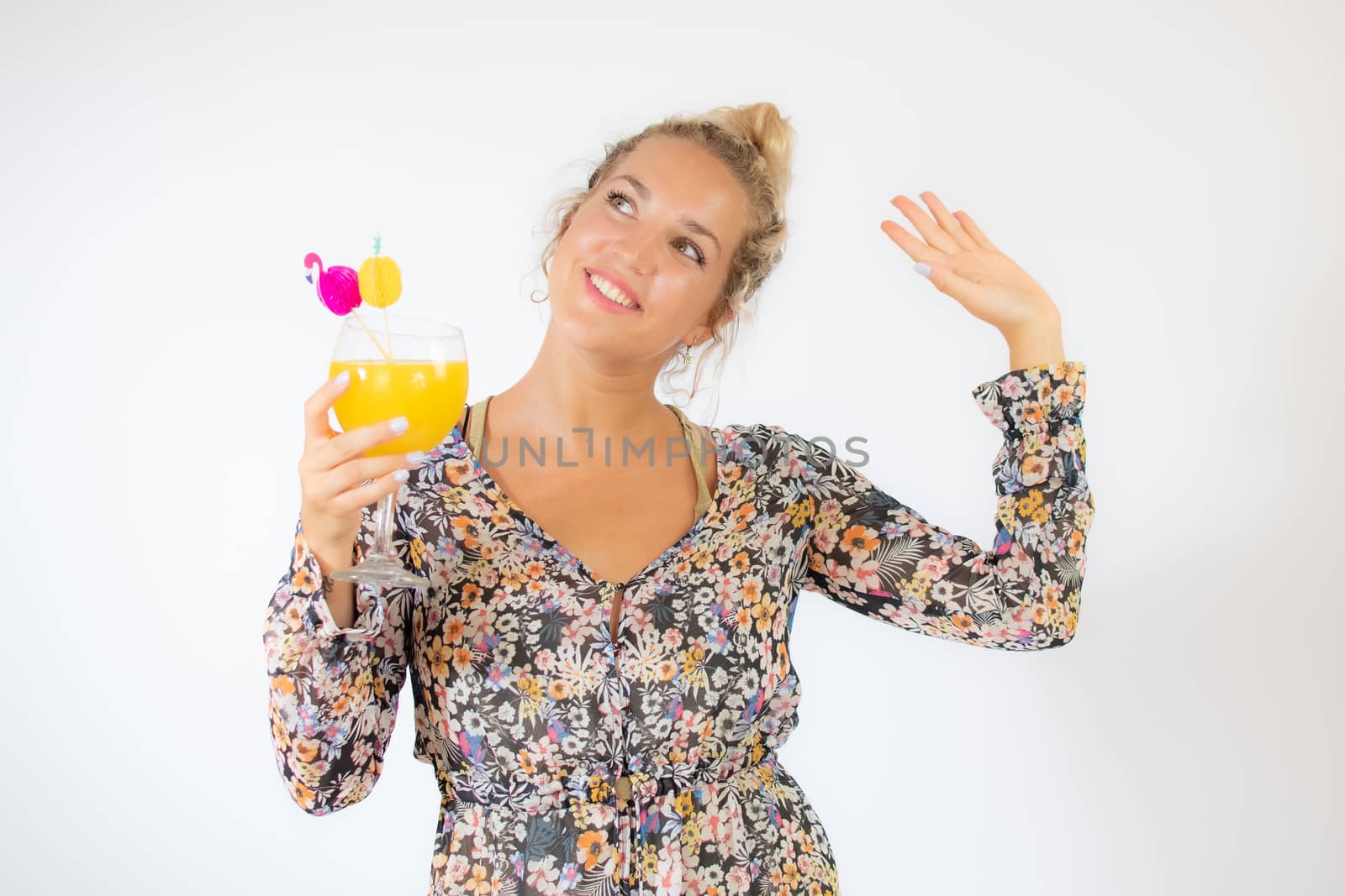 Pretty blonde woman in a flowery dress with a cocktail on white background