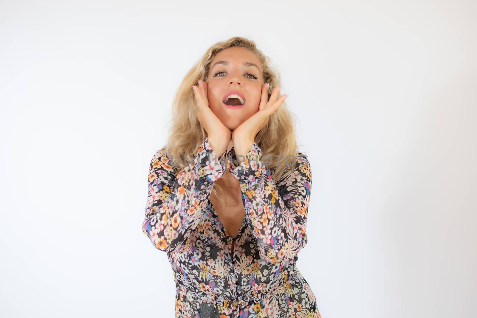 Pretty blonde woman in a flowery dress gesturing on white background