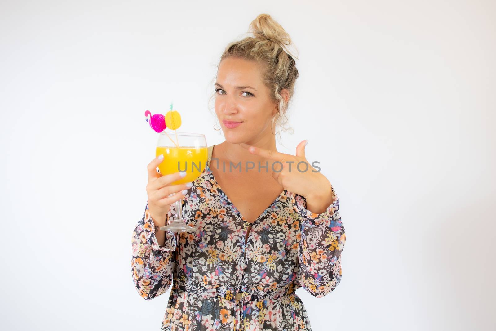 Pretty blonde woman in a flowery dress with a cocktail on white background