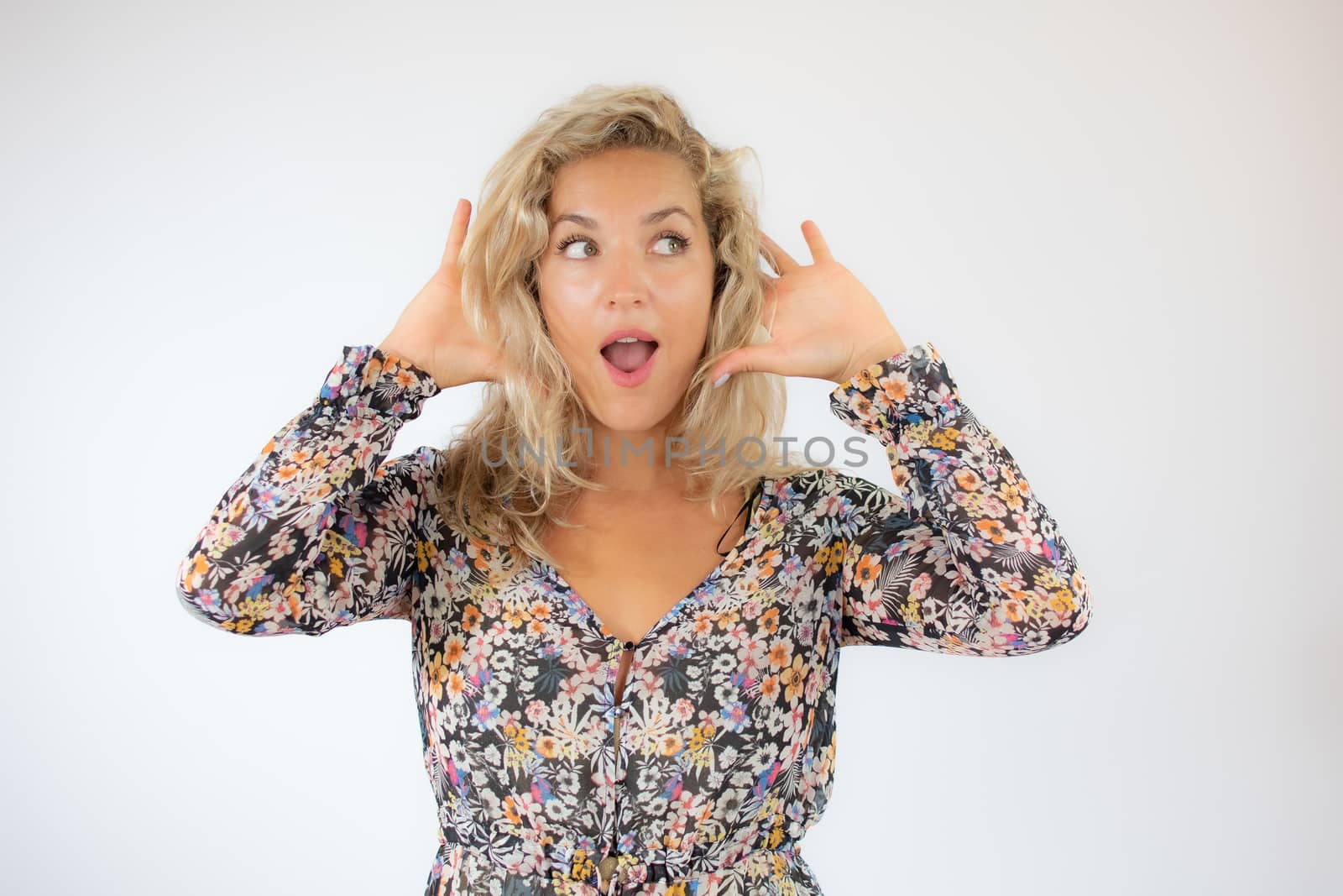 Pretty blonde woman in a flowery dress gesturing on white background