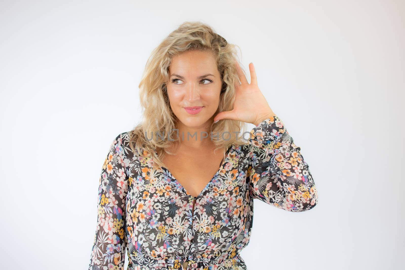 Pretty blonde woman in a flowery dress gesturing on white background