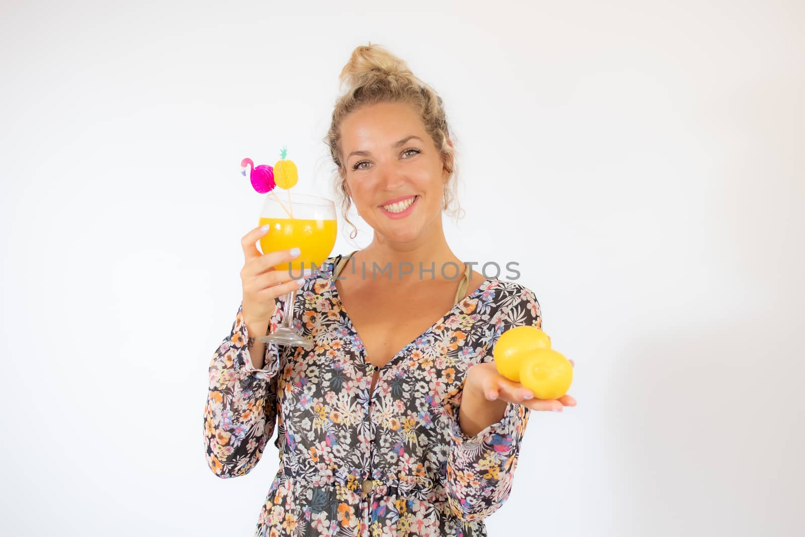 Pretty blonde woman in a flowery dress with a cocktail on white background