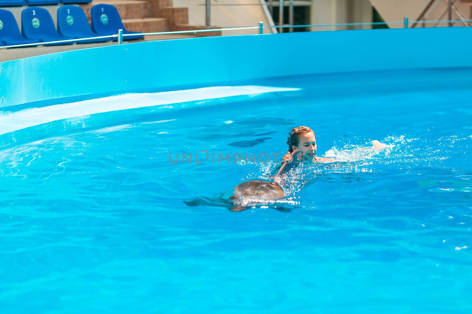 Happy little girl swimming with dolphins in Dolphinarium by Len44ik