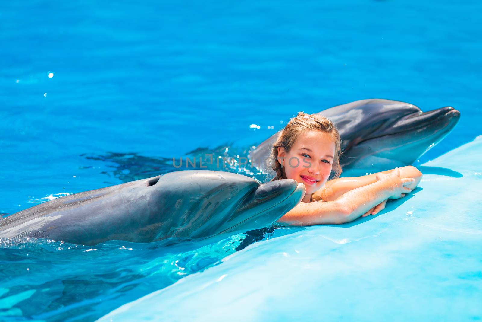 Happy little girl swimming with dolphins in Dolphinarium by Len44ik