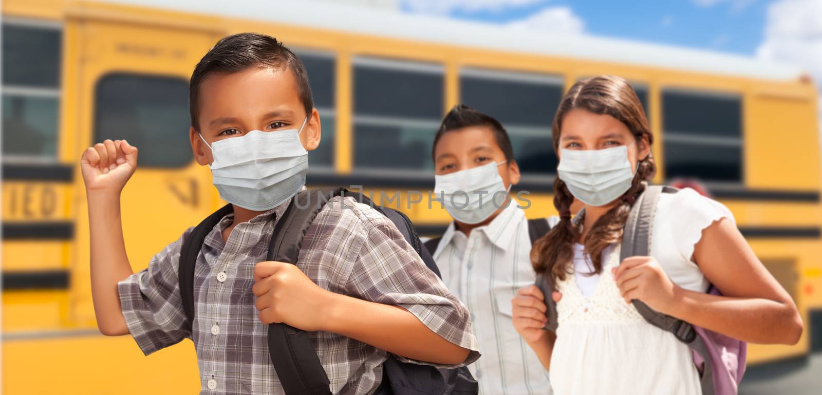 Hispanic Students Near School Bus Wearing Face Masks.