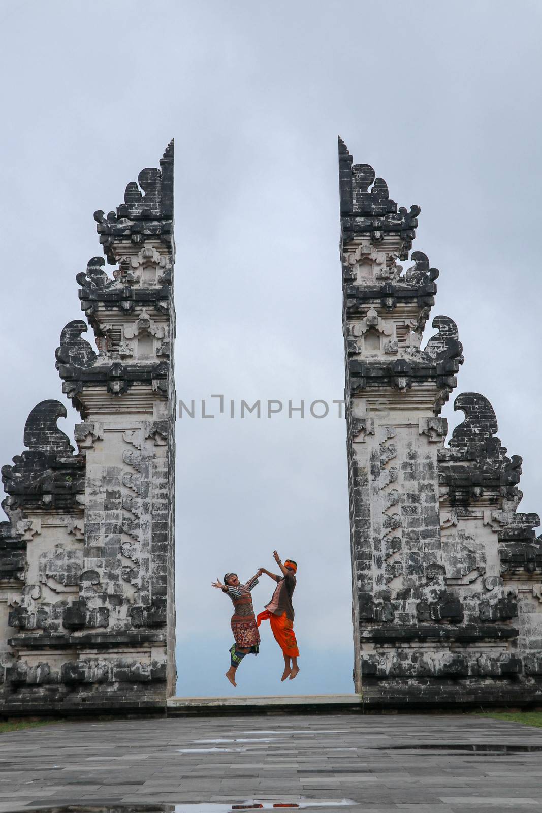 Happy young couple jumping in temple gates of heaven. Perfect Honeymoon concept. Lempuyang Luhur temple in Bali, Indonesia.