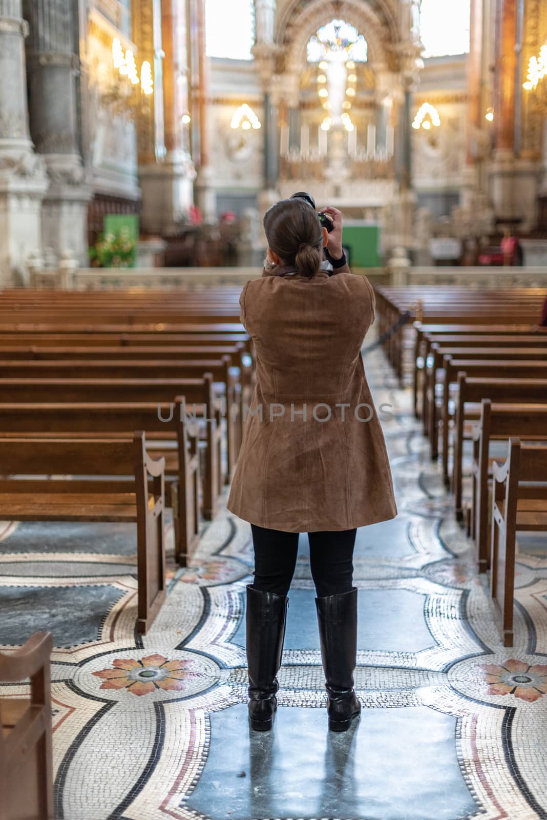 Lyon, France -- November 6, 2017 -- A photographer focuses her camera to get a shot in a church. Editorial Use Only