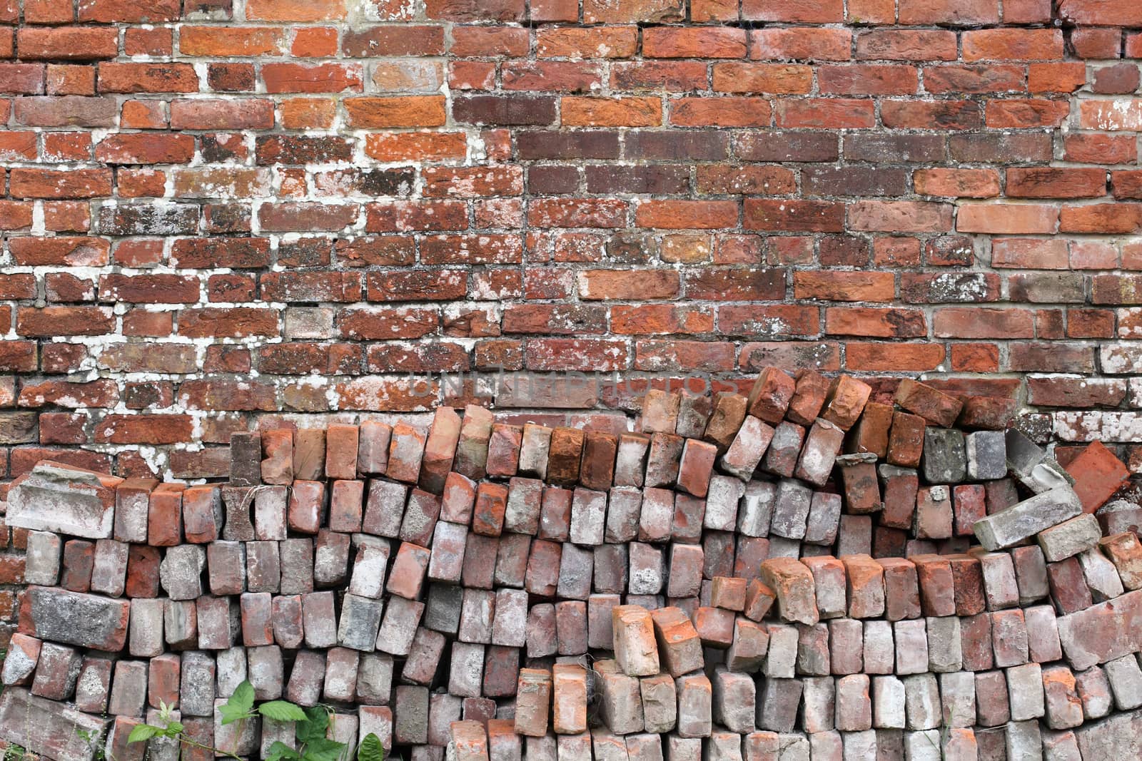 Old distressed red brick wall background texture with a pile of bricks in the foreground