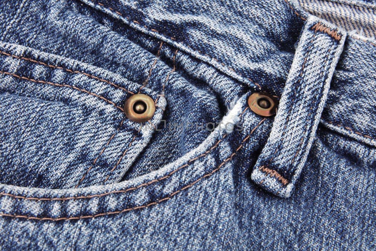 A blue jeans close up detail showing front pocket and waist band and belt loop and studs