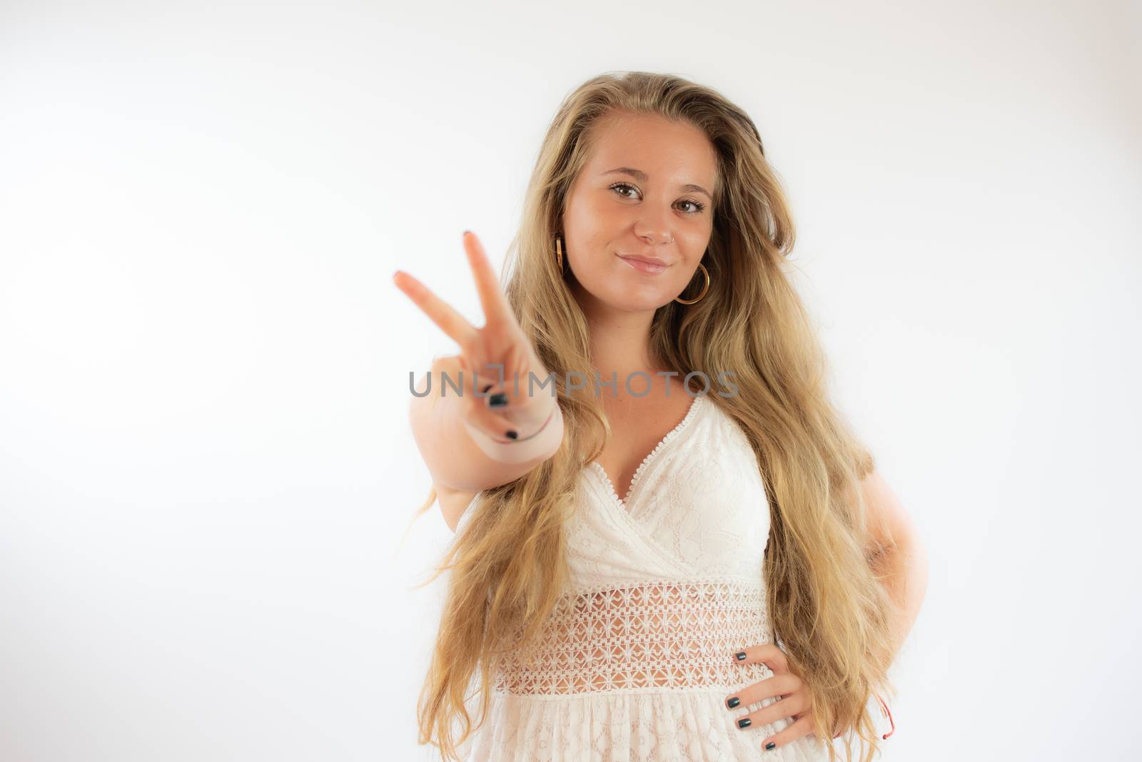 Pretty blonde girl in a white dress making the victory gesture