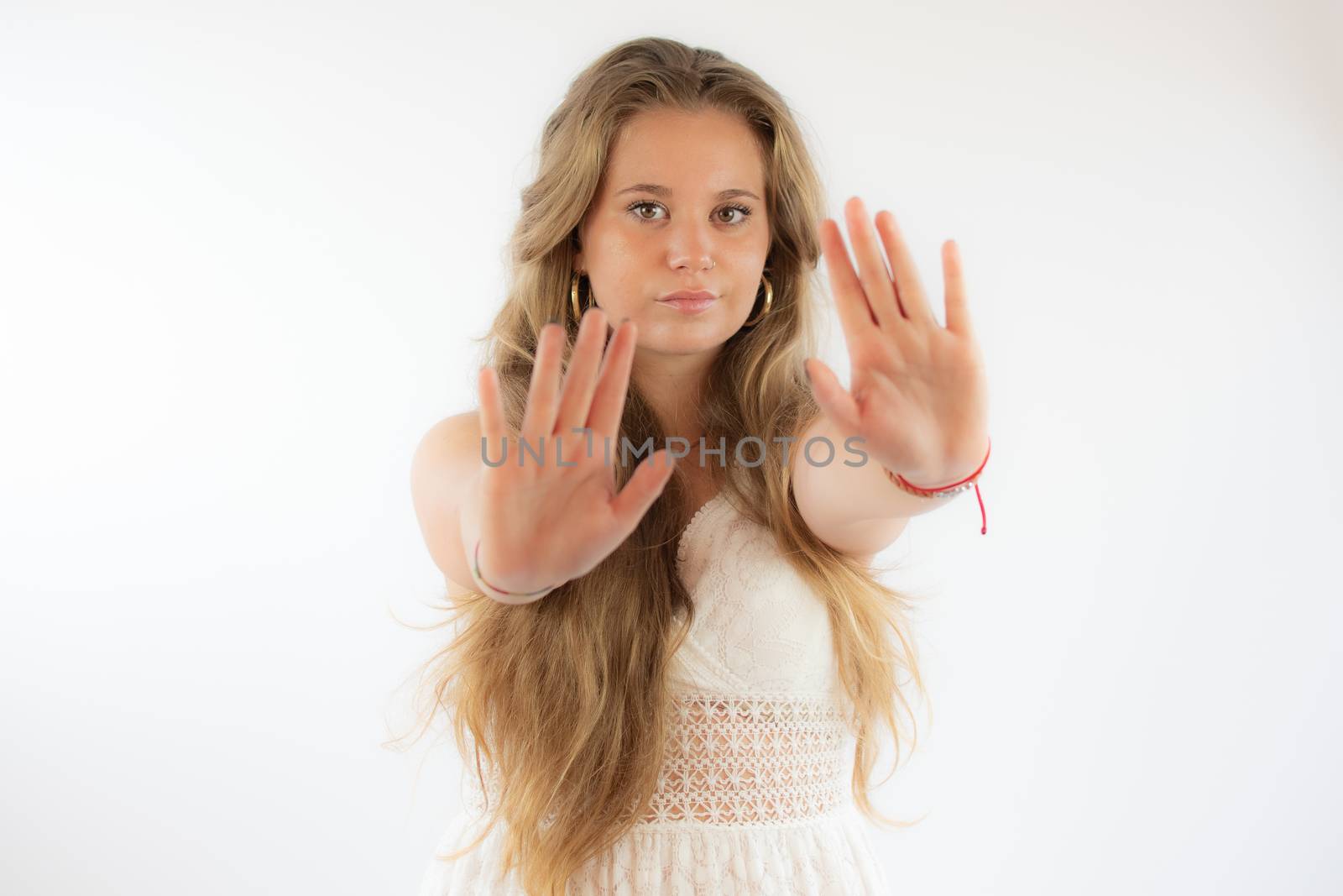 Pretty blonde girl in a white dress making stop gesture with her hands