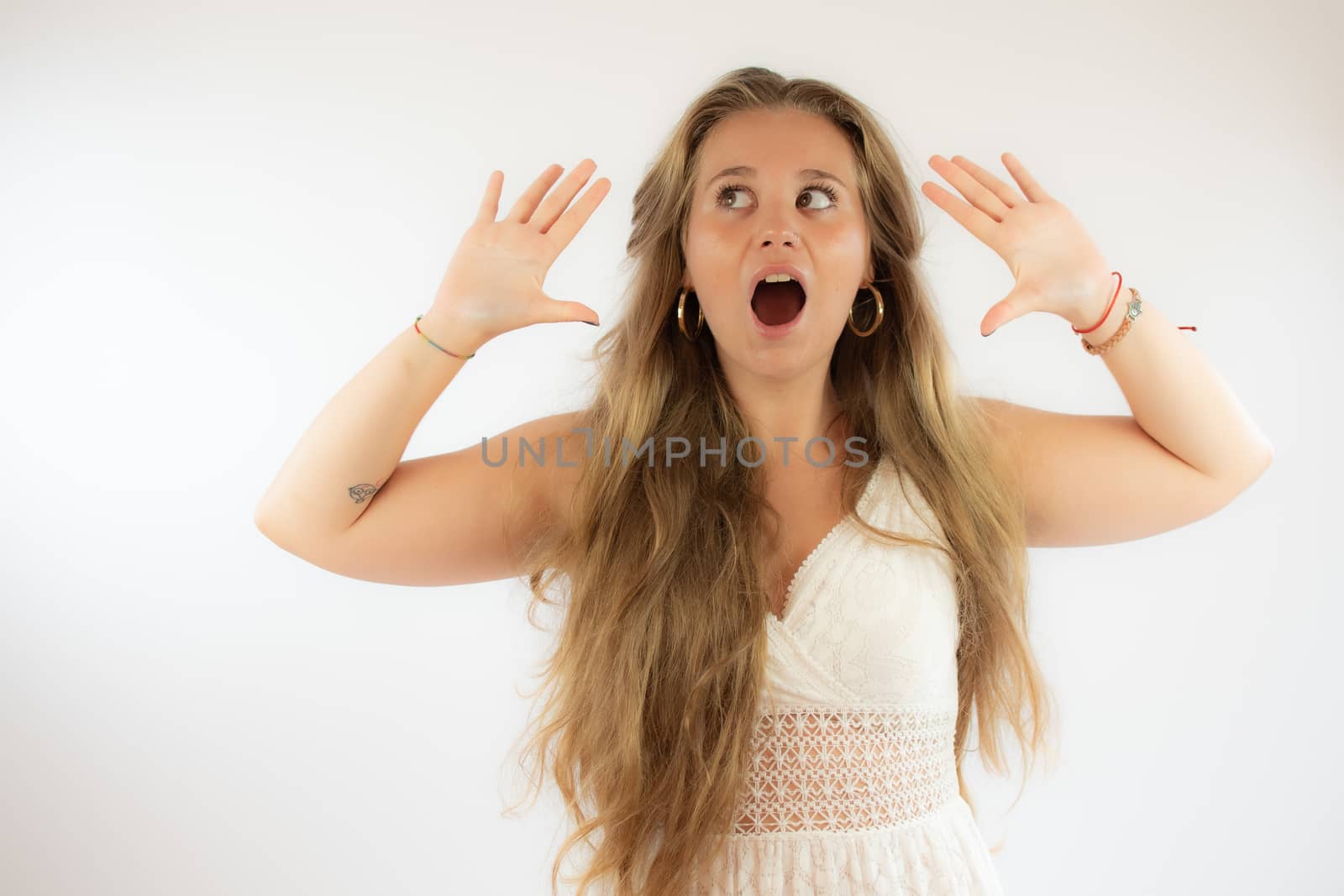 Pretty blonde girl in a white dress with surprised gesture