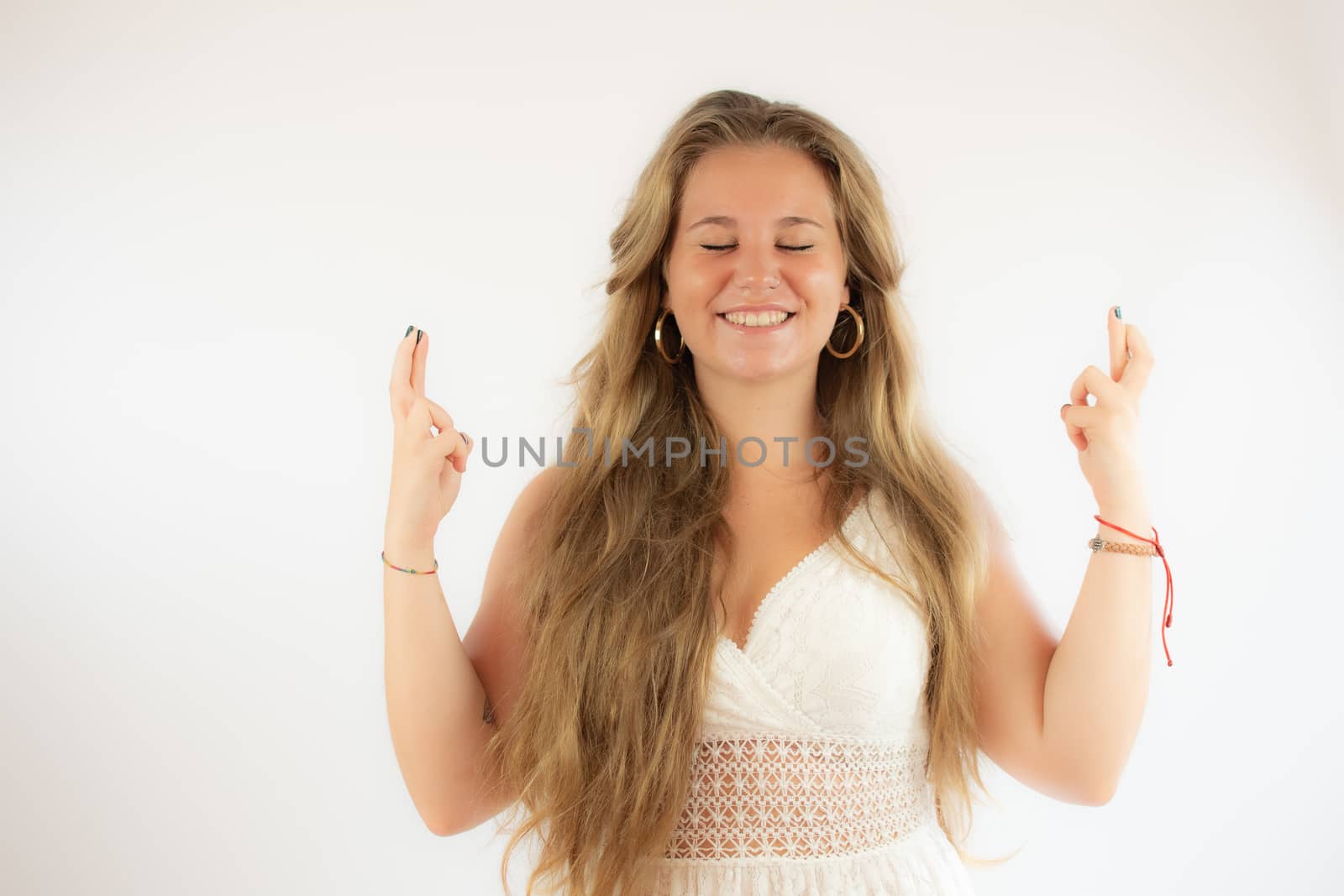 Pretty blonde girl in a white dress with her fingers crossed