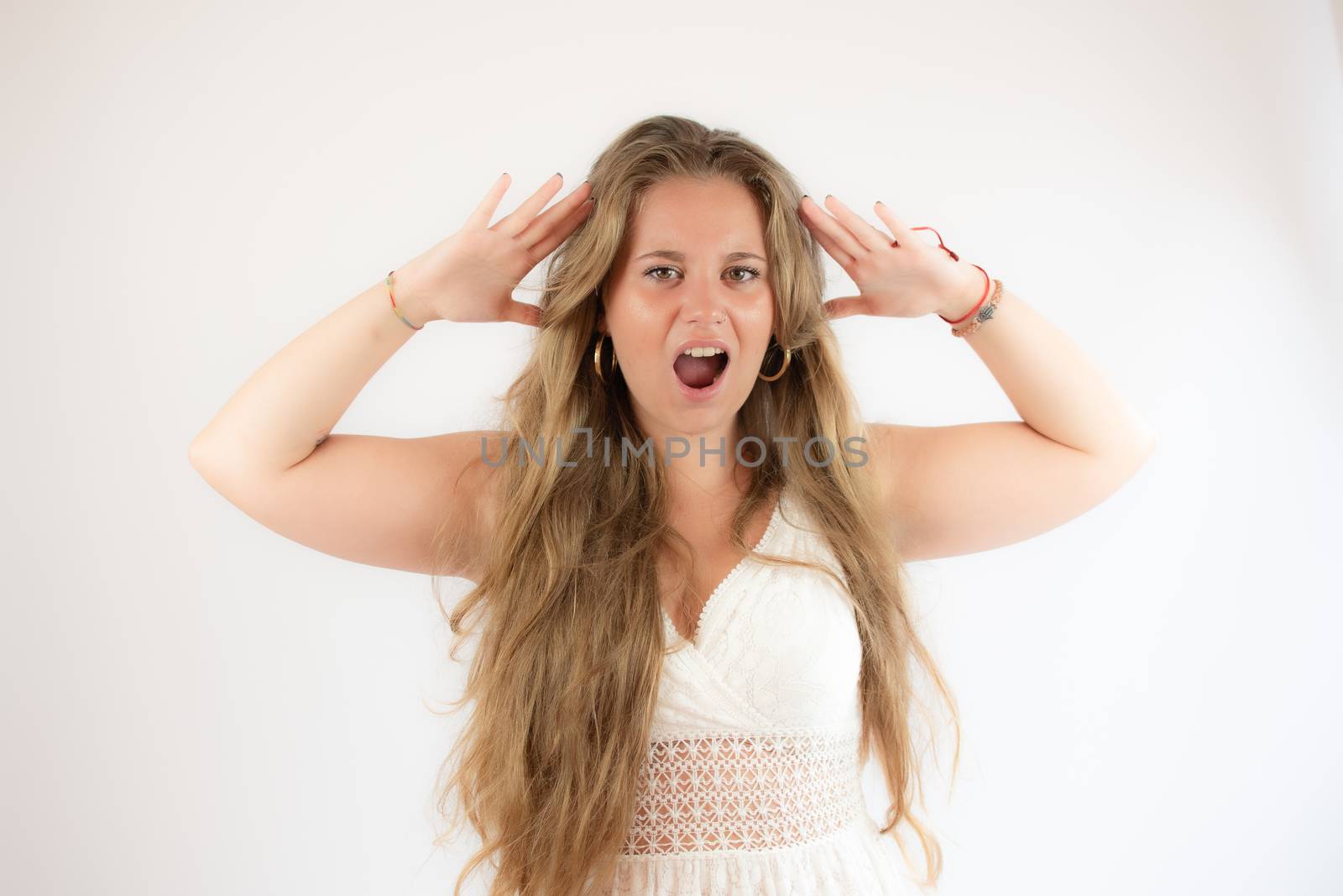 Pretty blonde girl in a white dress with angry gesture