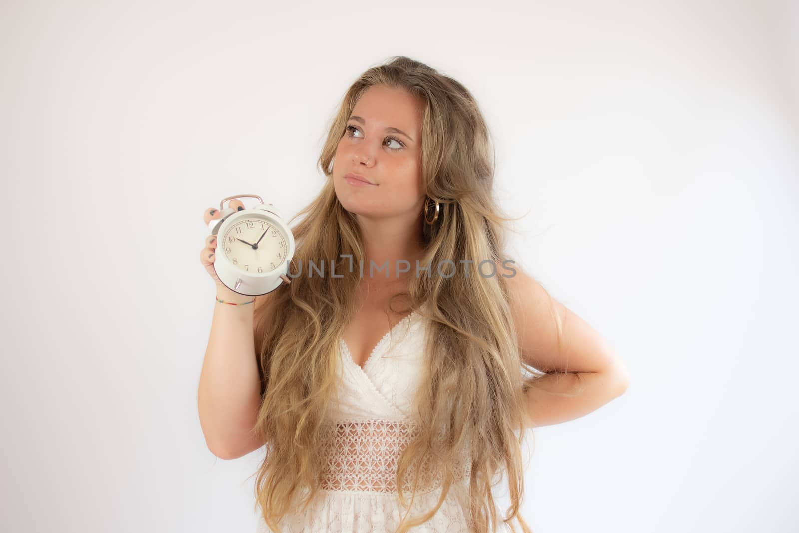 Pretty blonde girl in a white dress showing a clock