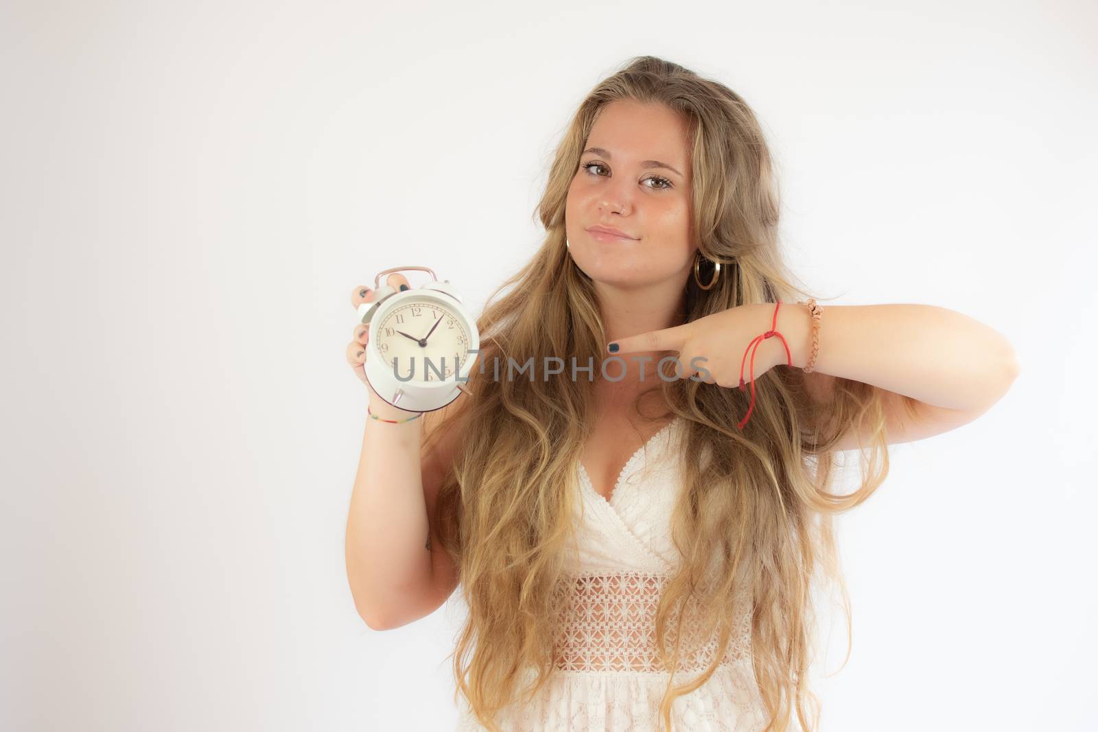 Pretty blonde girl in a white dress showing a clock