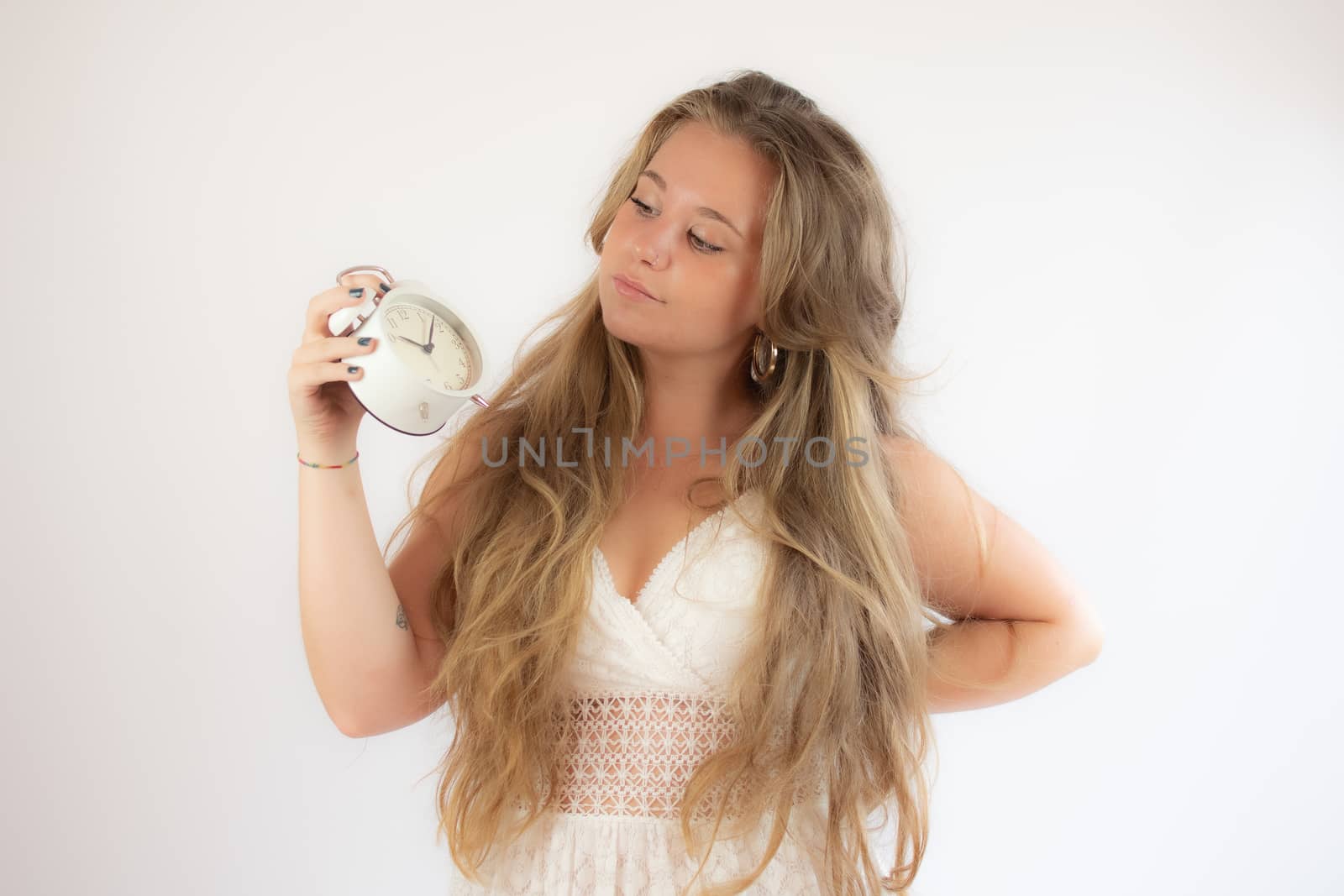 Pretty blonde girl in a white dress showing a clock