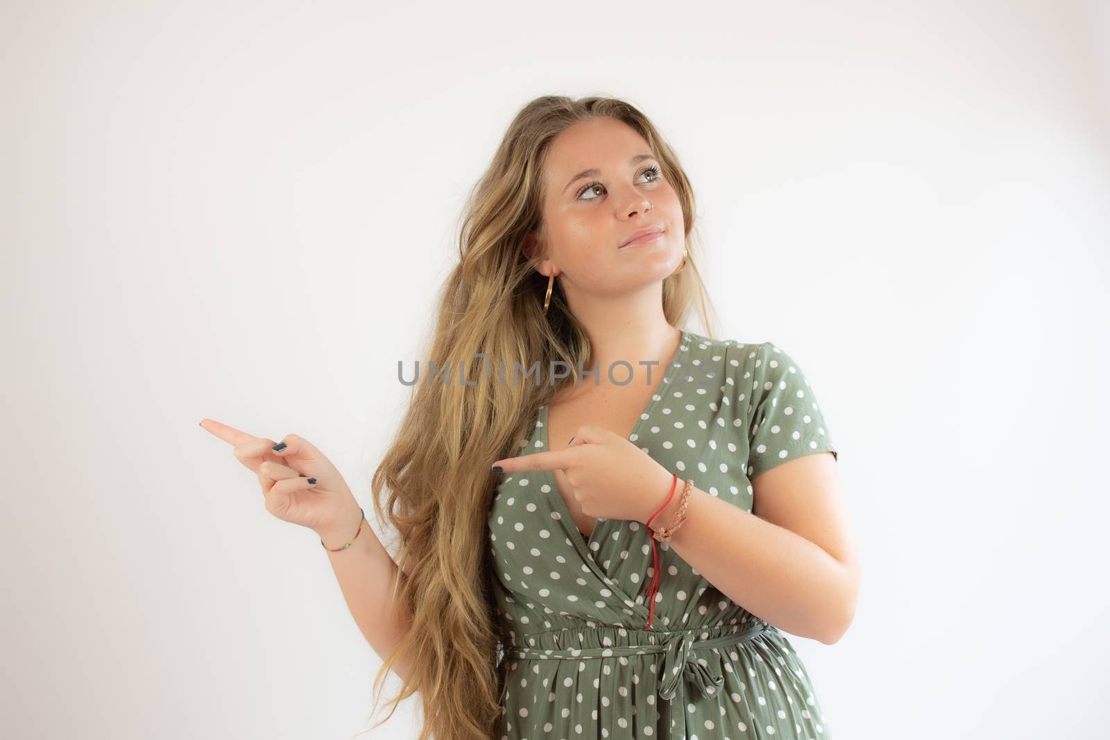 Beautiful young girl with long hair and smiling face and pointing with her fingers