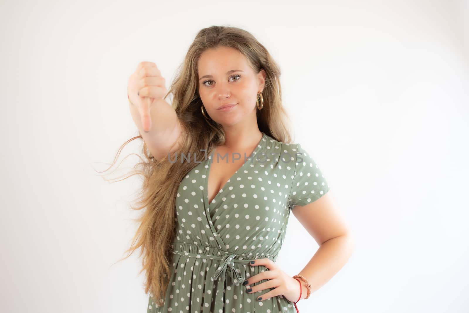 Pretty blonde girl in a green dress making finger down gesture