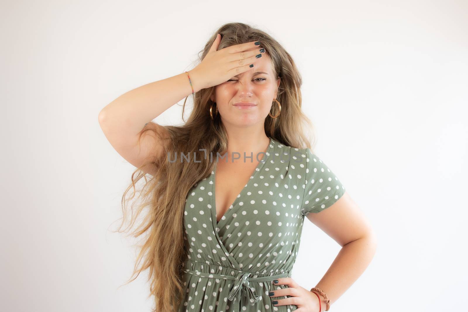 Pretty blonde girl in a green dress with the gesture of concern