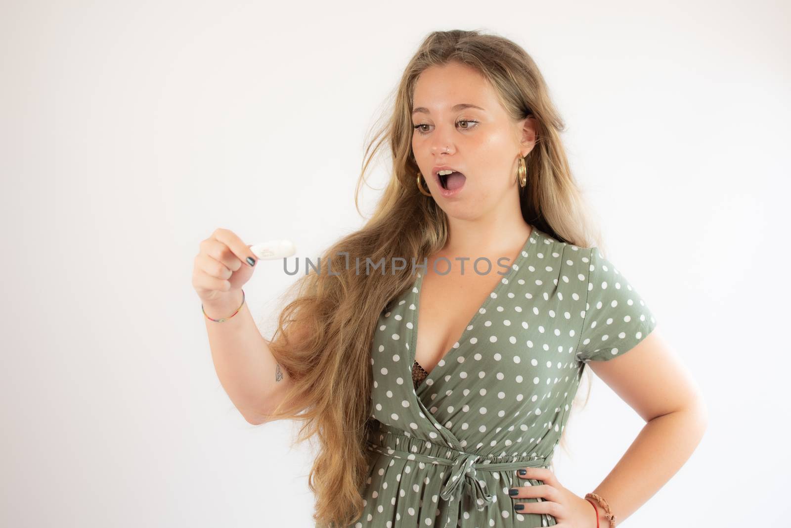 Pretty blonde girl in a green dress looking the test with the gesture of concern