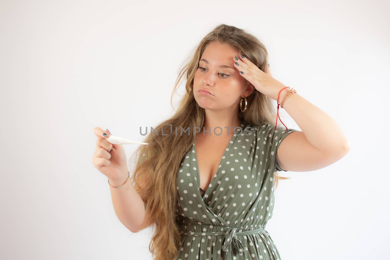 Pretty blonde girl in a green dress looking the test with the gesture of concern
