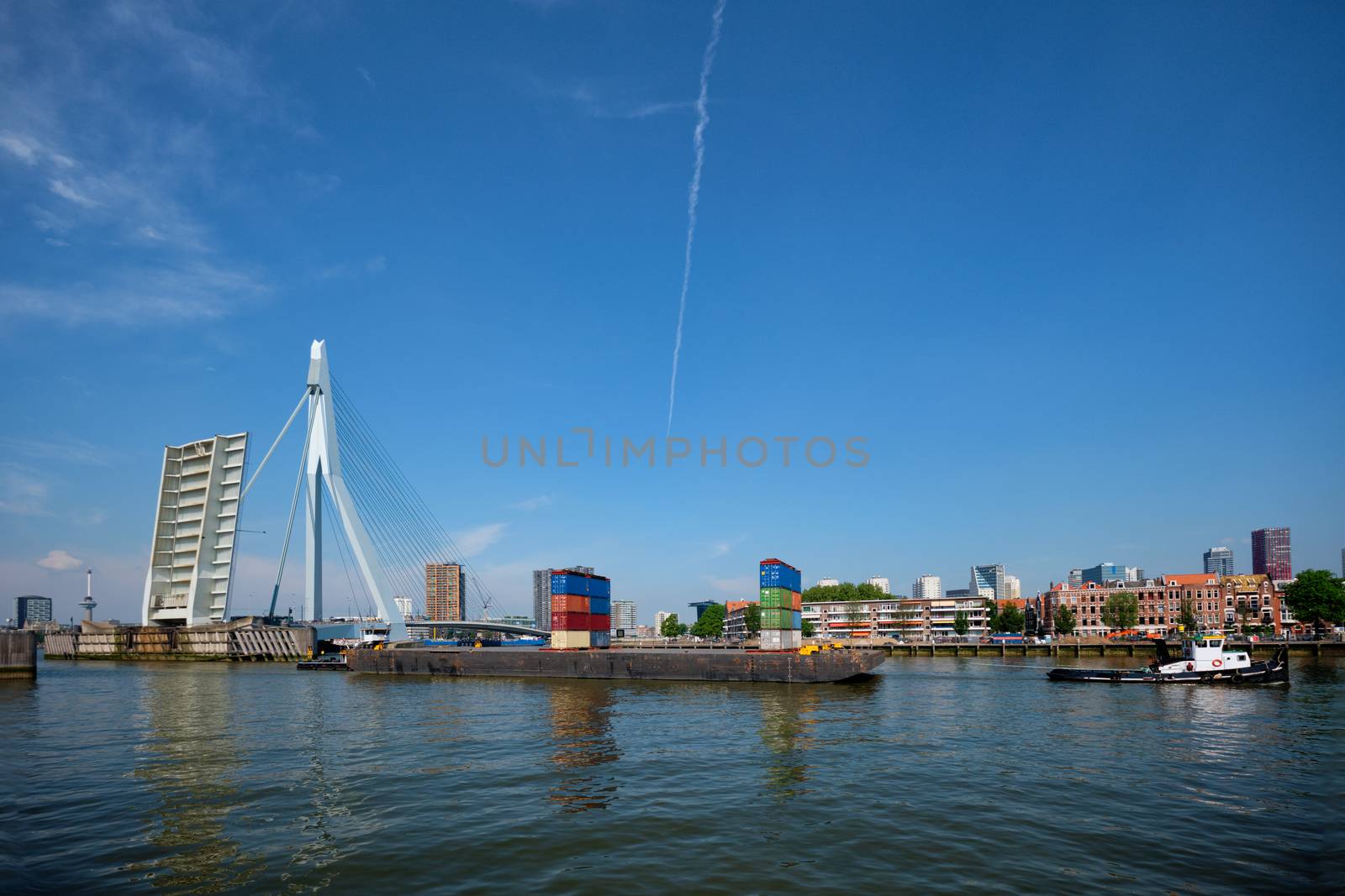 Tug boat towing barge with containers under open bascule part of Erasmusbrug bridge in Nieuwe Maas river. Rotterdam, Netherlands