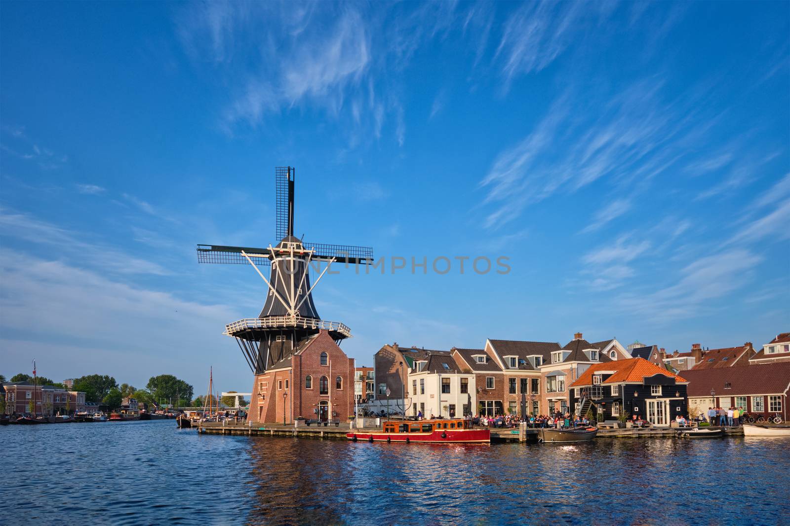 Harlem cityscape - landmark windmill De Adriaan on Spaarne river with boats. Harlem, Netherlands