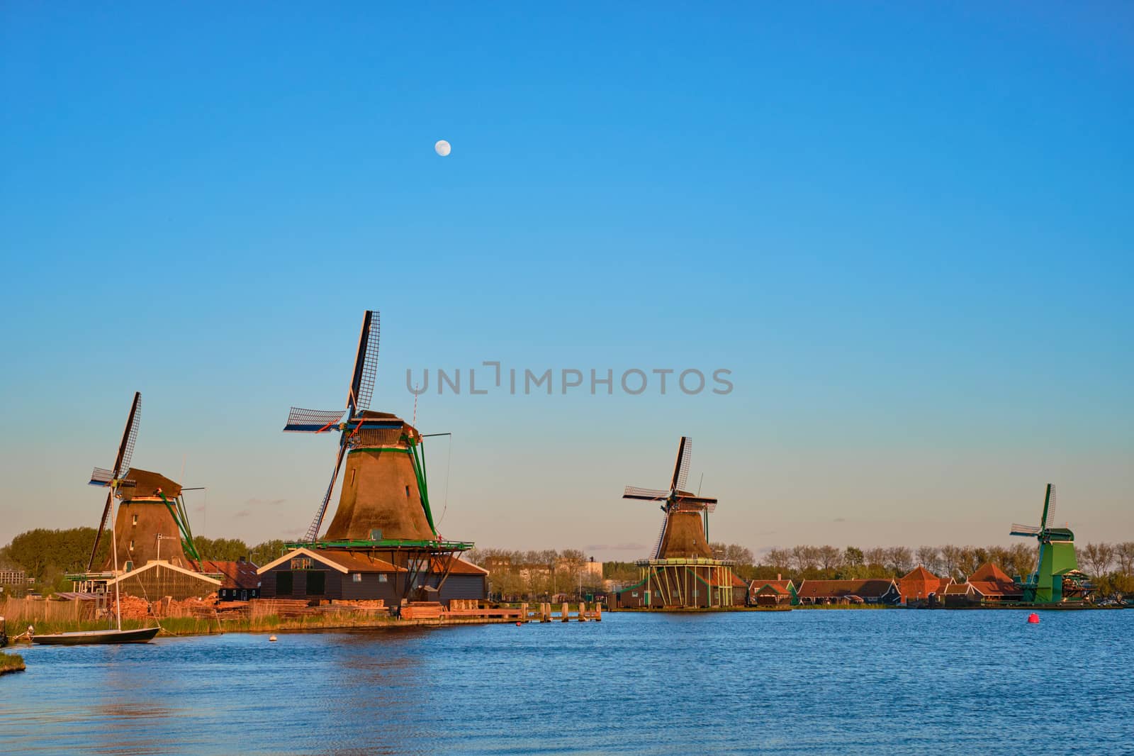 Windmills at famous tourist site Zaanse Schans in Holland in twilight on sunset with moon. Zaandam, Netherlands