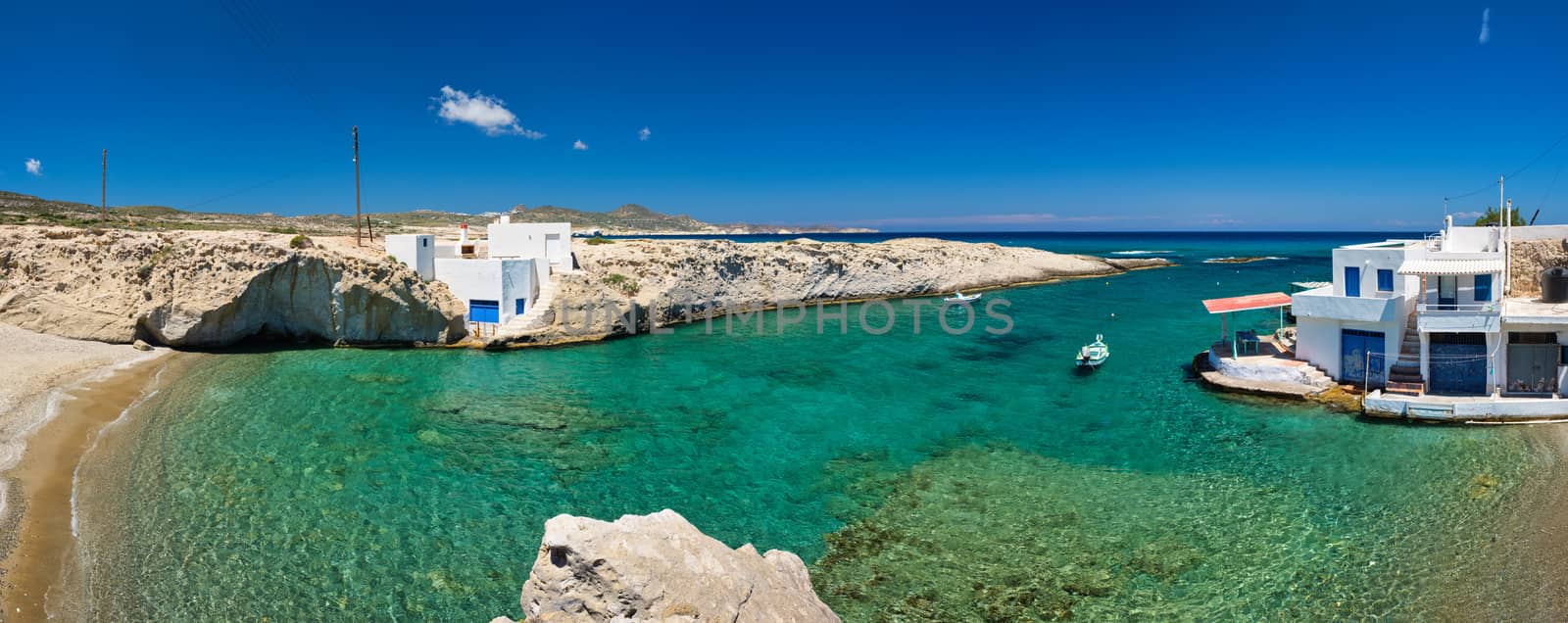 Greece scenic island panorama - small harbor with fishing boats in crystal clear turquoise water, traditishional whitewashed house. MItakas village, Milos island, Greece.