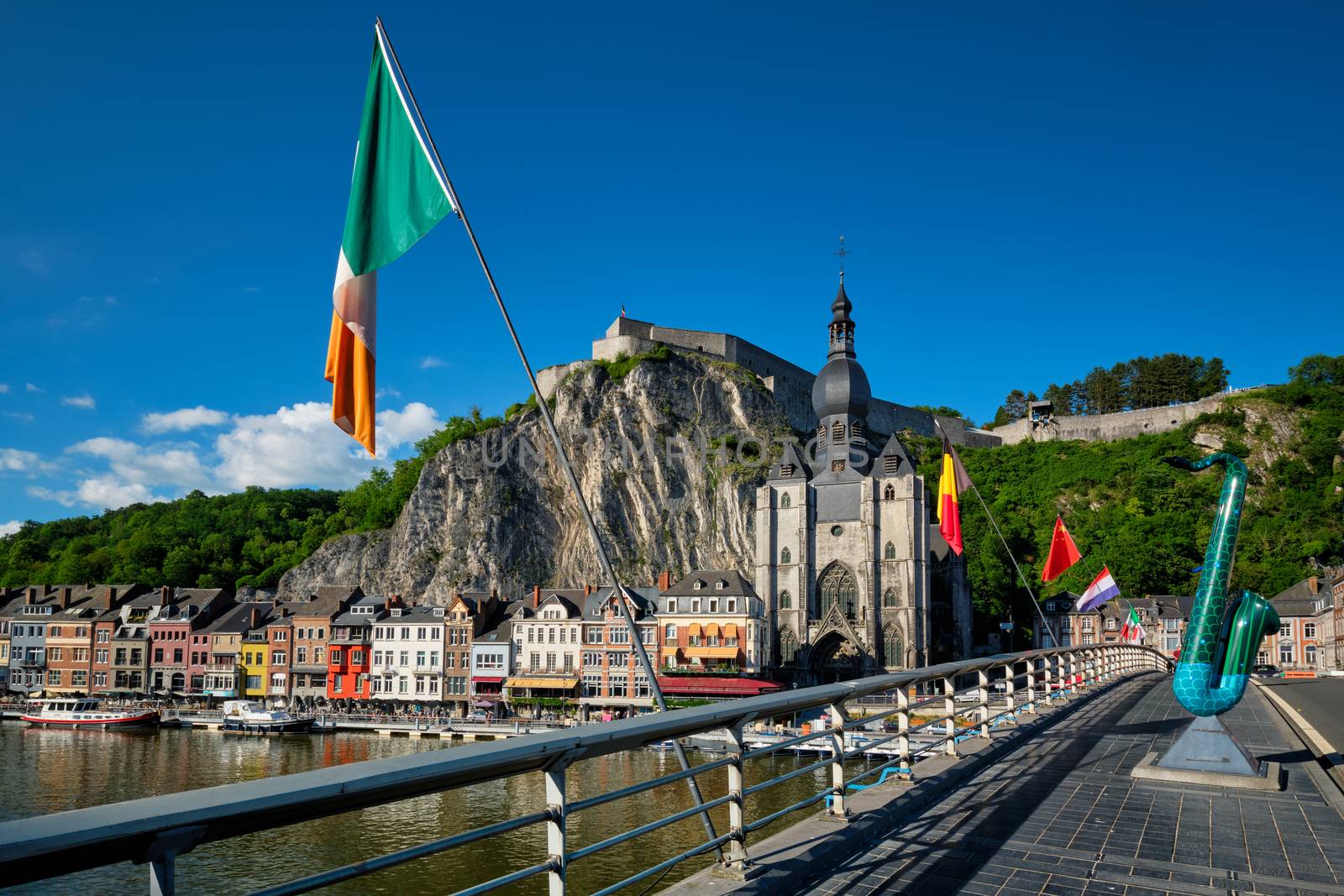 Picturesque Dinant town, Dinant Citadel and Collegiate Church of Notre Dame de Dinant and Charles de Gaulle bridge with saxophones as Dinant is hometown of saxophone inventor and flags. Namur, Blegium