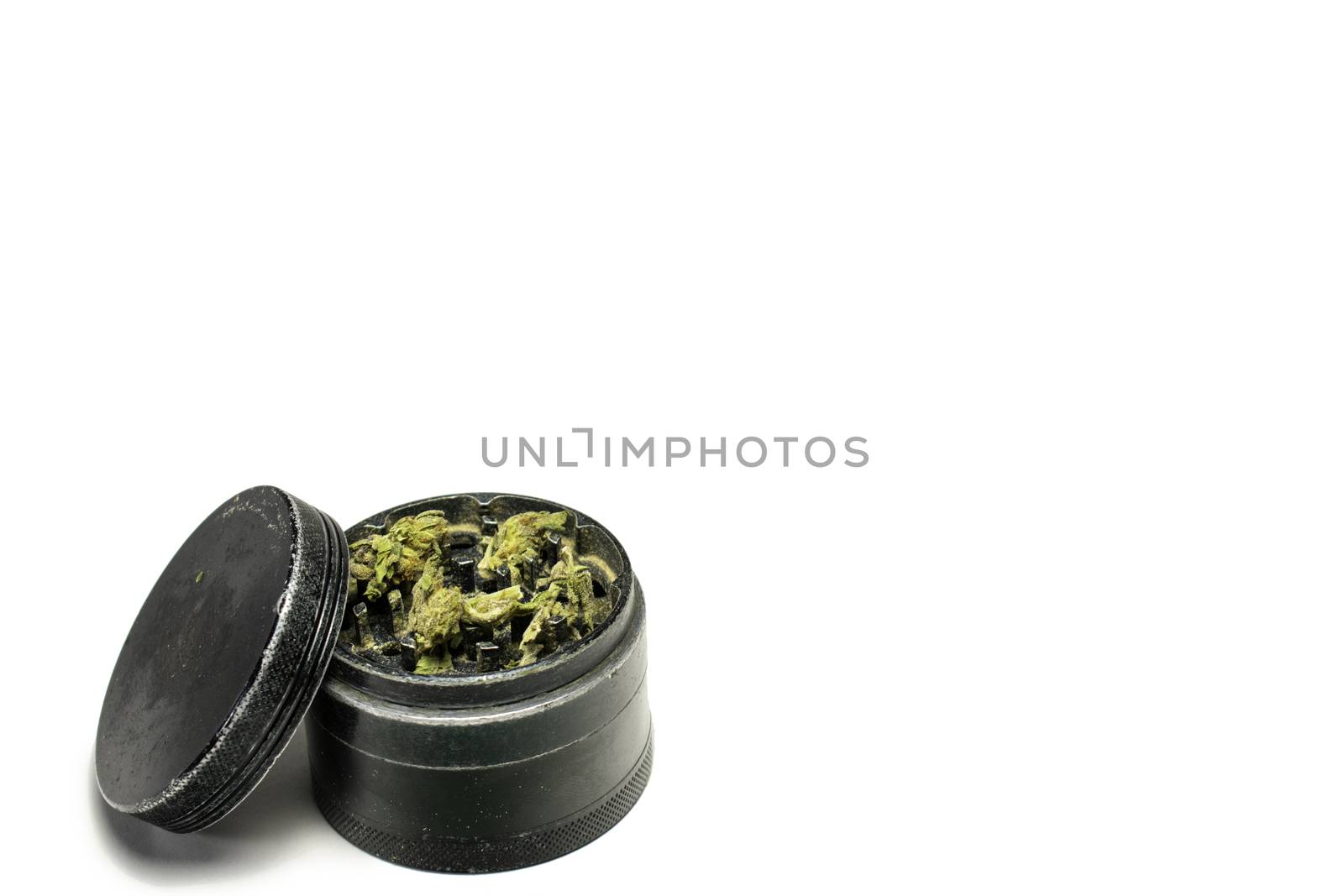 The Top Chamber of a Black and Used Grinder Full of Marijuana on a Pure White Background