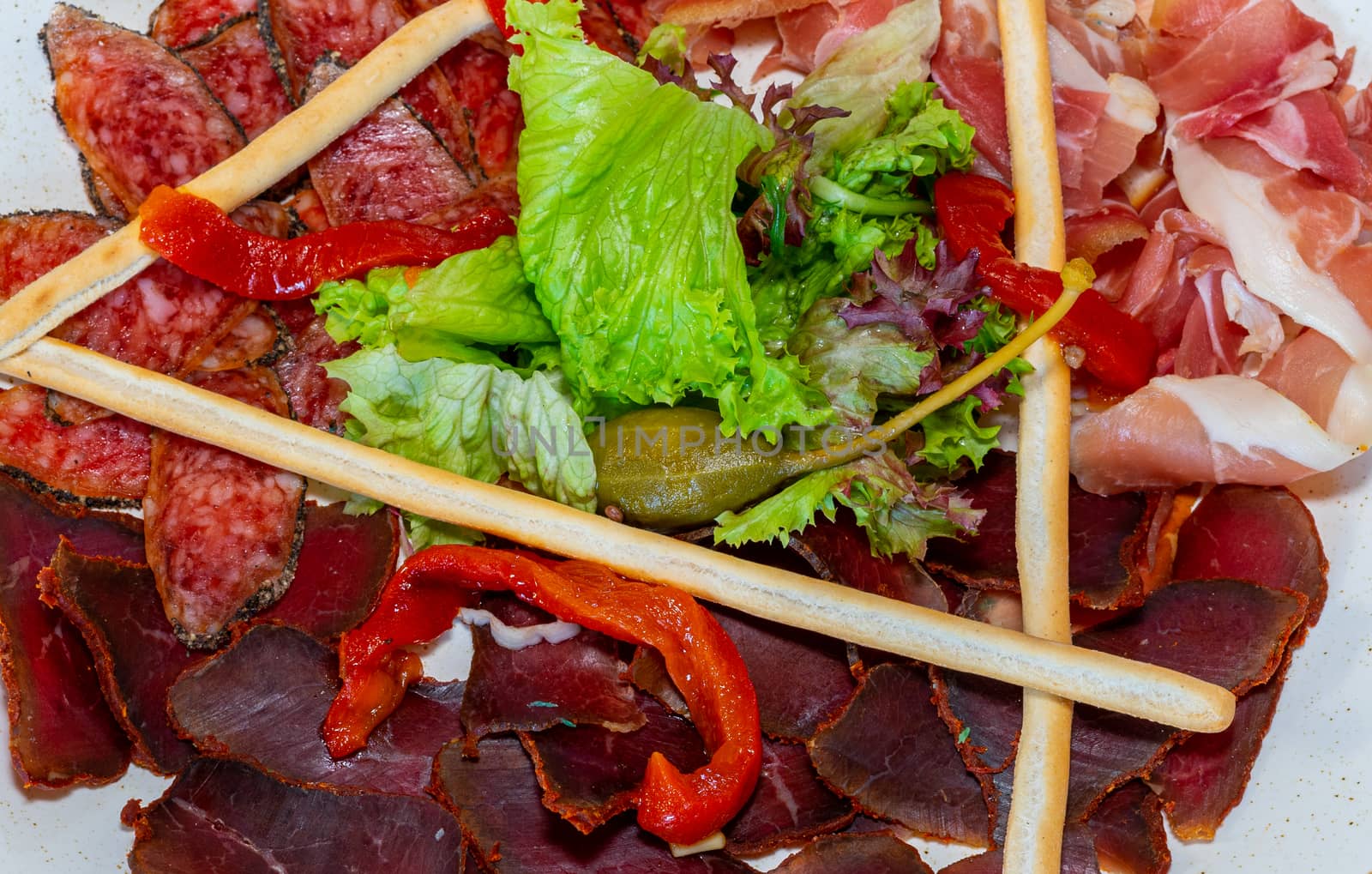 Trio of dried delicacies. Basturma, prosciutto, sausage flat. Plate with delicacies